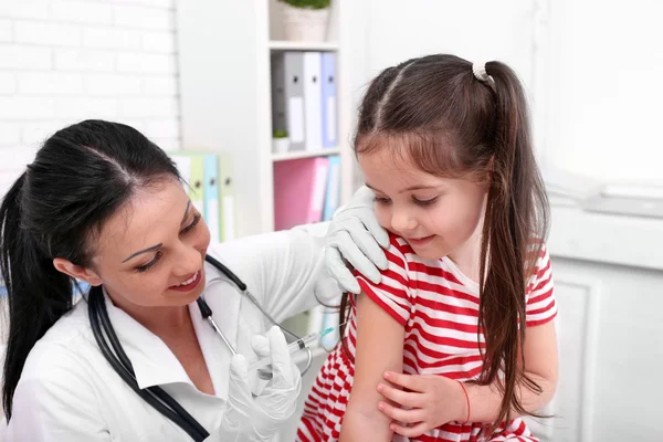 Ofiste bir çocuk enjeksiyon veren doktor