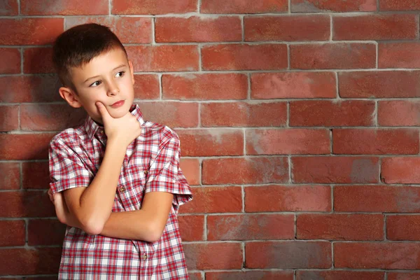 Niedlichen kleinen Jungen auf Backsteinmauer Hintergrund. Kindermode-Konzept — Stockfoto