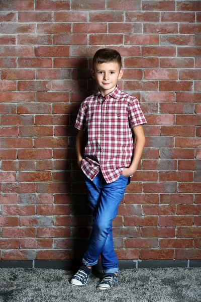 Χαριτωμένο μικρό αγόρι σε φόντο τούβλο τοίχων. Έννοια της μόδας τα παιδιά — Φωτογραφία Αρχείου