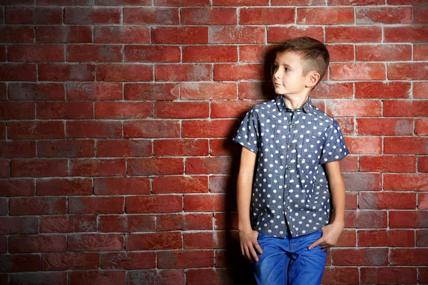 Niedlichen kleinen Jungen auf Backsteinmauer Hintergrund. Kindermode-Konzept — Stockfoto