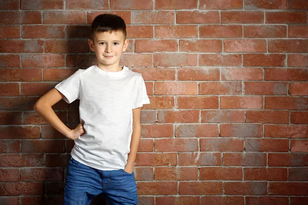 Niedlichen kleinen Jungen auf Backsteinmauer Hintergrund. Kindermode-Konzept — Stockfoto