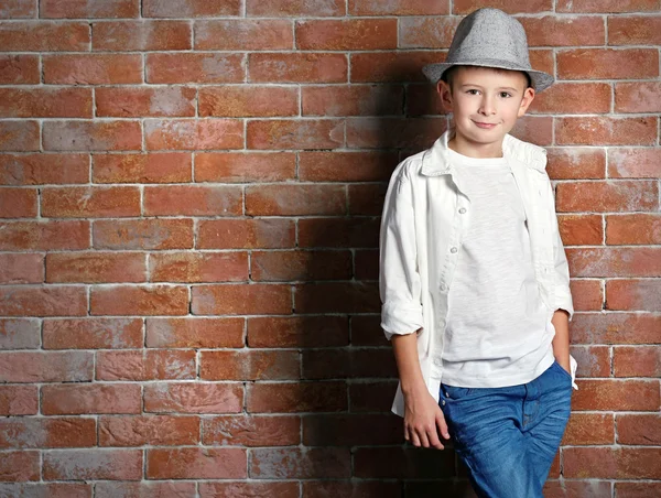 Söt liten pojke på tegel vägg bakgrund. Kids fashion-konceptet — Stockfoto