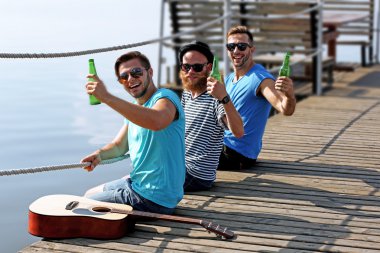 İskelede oturup ve birbirleriyle konuşmak genç erkekler