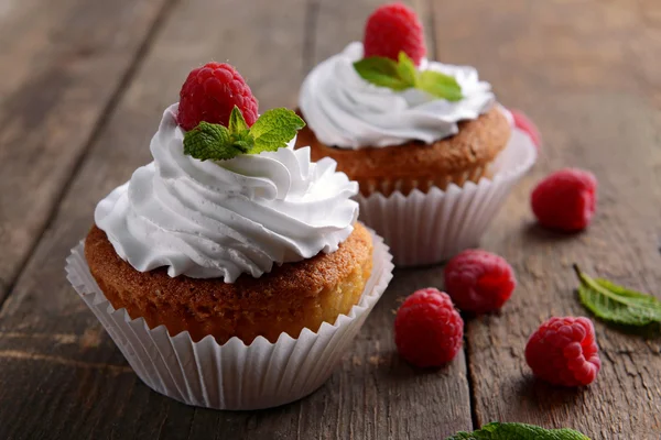 Delicious cupcakes with berries and fresh mint on wooden table close up — Stock Photo, Image