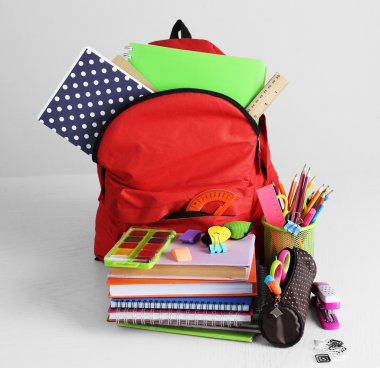Tahta masada okul malzemeleriyle dolu sırt çantası. 