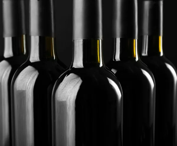 Wine bottles in a row on black  background, close up — Stock Photo, Image