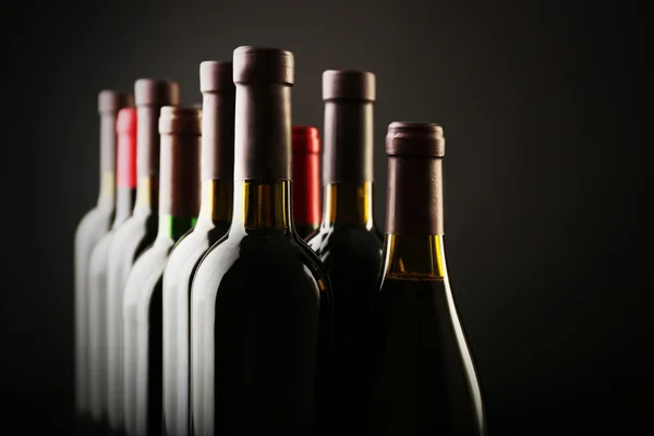 Garrafas de vinho em uma fileira no fundo escuro, close-up — Fotografia de Stock