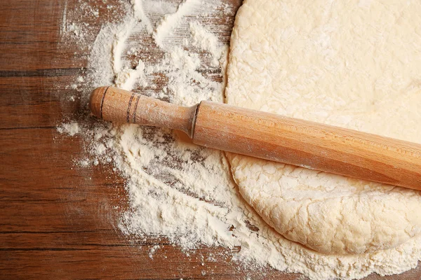 Тесто для пиццы и булавки на деревянном столе — стоковое фото