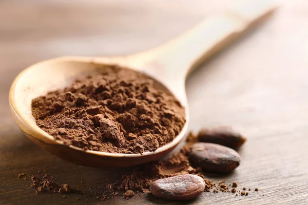 Cucchiaio di legno con cacao in polvere sul tavolo, primo piano — Foto Stock