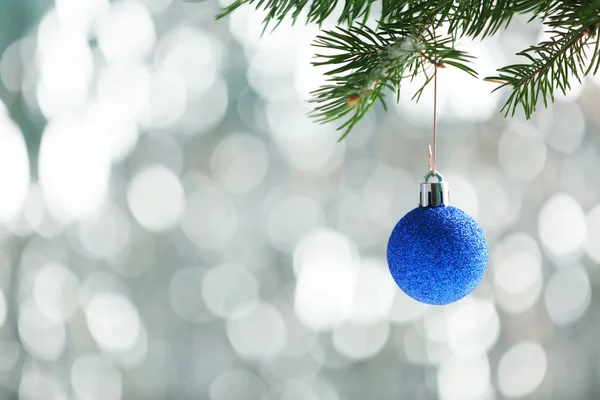 Christmas blue bauble on a fir branch and glitter background — Stock Photo, Image