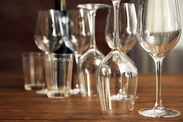 Construction of empty wine glasses on wooden table against blurred background — Stock Photo, Image