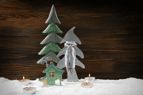 Dos abetos, velas y casa en la nieve sobre fondo de madera, naturaleza muerta —  Fotos de Stock