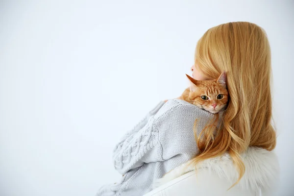 Young woman with red cat sitting on chair against white background, close up, back view — Stock Photo, Image