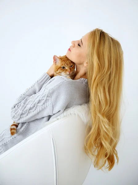 Kırmızı kedi beyaz arka plan, sandalye üzerinde oturan genç kadınla yakın çekim — Stok fotoğraf