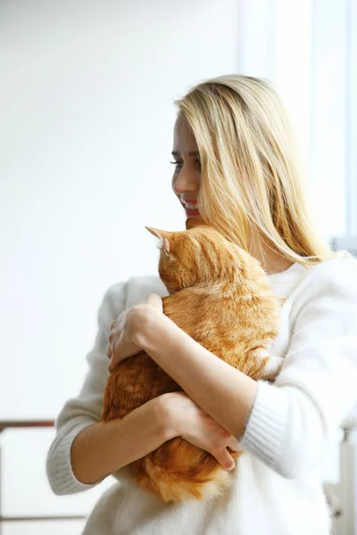 Jovem mulher segura gato vermelho nas mãos, close-up — Fotografia de Stock