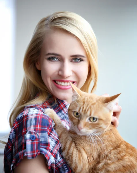 Mujer joven posando con gato rojo en las manos, de cerca — Foto de Stock