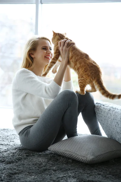 Çekici genç kadın yerde kırmızı kedi ile oynarken — Stok fotoğraf