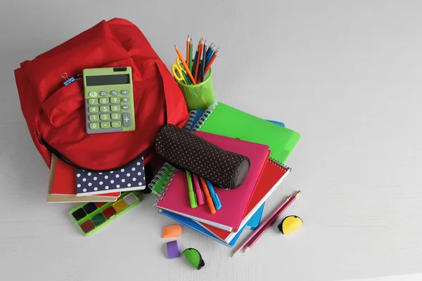 Ryggsäck med skolmaterial på träbord — Stockfoto