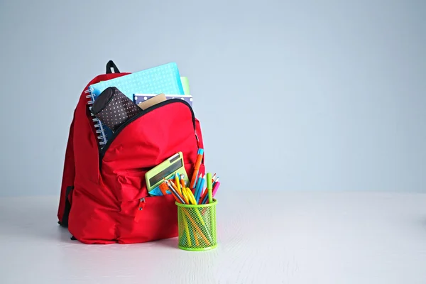Plecak z materiałami szkolnymi na drewnianym stole — Zdjęcie stockowe