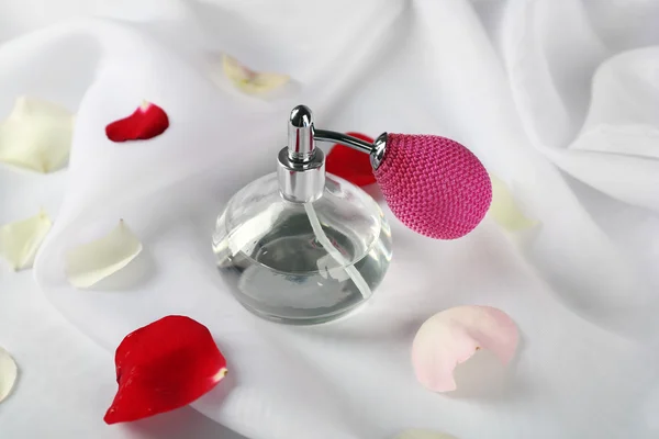 Bottle of perfume and rose petals on fabric background — Stock Photo, Image