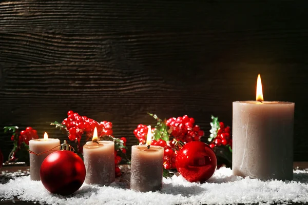 Bougies allumées et accessoires de Noël avec neige sur fond en bois — Photo