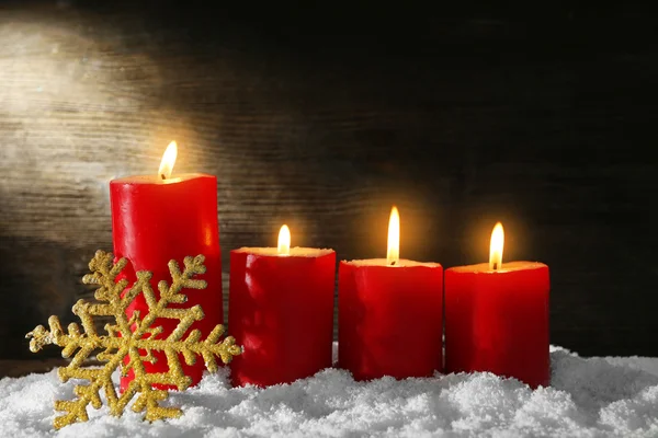 Velas ardientes y copo de nieve con nieve sobre fondo de madera —  Fotos de Stock