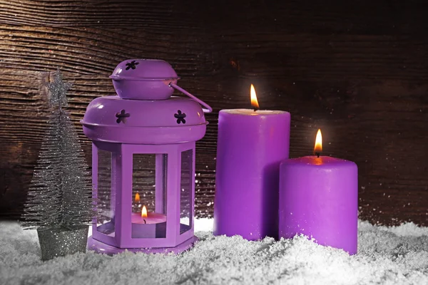 Горящие фиолетовые свечи со снегом на деревянном фоне — стоковое фото