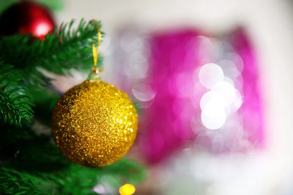 Natal bugiganga dourada em um abeto sobre fundo borrado, close-up — Fotografia de Stock