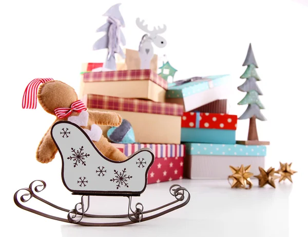 Сани на фоне красивых новогодних подарков с игрушками, изолированными на белом — стоковое фото