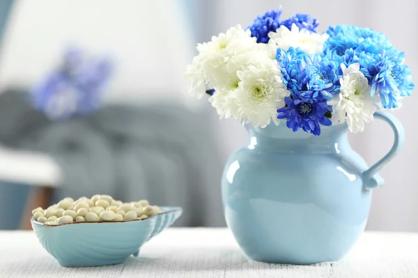 Glas mit Blumen und Schale mit Süßigkeiten — Stockfoto