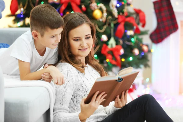 Mamma che legge libro a figlio vicino all'albero di Natale — Foto Stock
