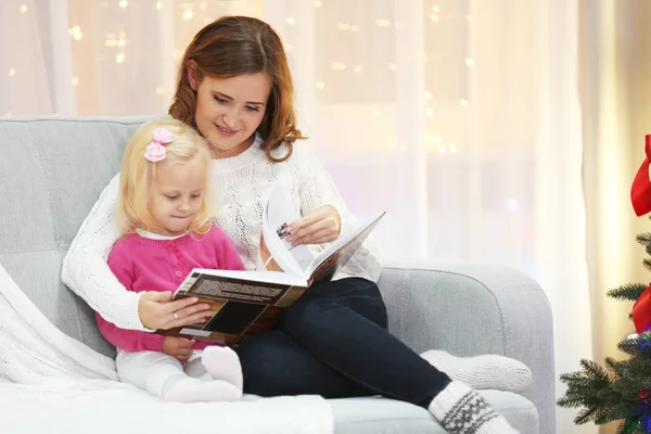 クリスマスのリビング ルームで娘にお母さん読書 — ストック写真