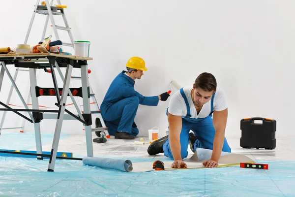 Рабочие обновляют квартиру на настенном фоне — стоковое фото
