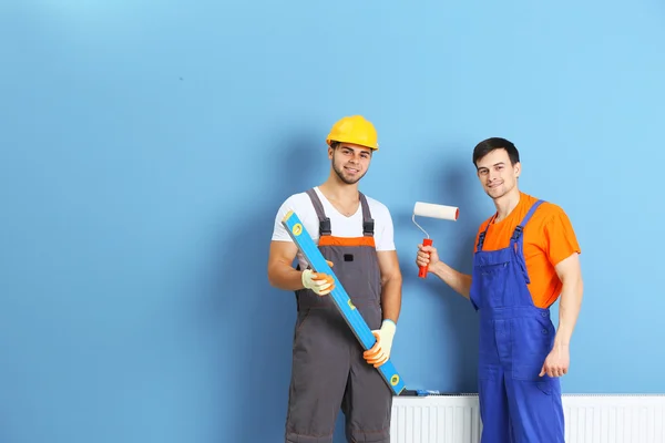 Dos trabajadores renovando apartamento en el fondo de la pared —  Fotos de Stock