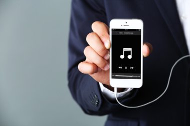 Gri arka plan üzerinde işadamı elinde müzik smartphone