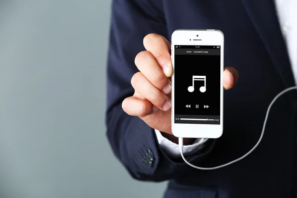 Music smartphone in businessman hand, on grey background — Stock Photo, Image