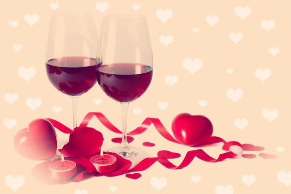Состав с красным вином в стаканах, красная роза, лента и декоративные сердца на бежевом фоне — стоковое фото