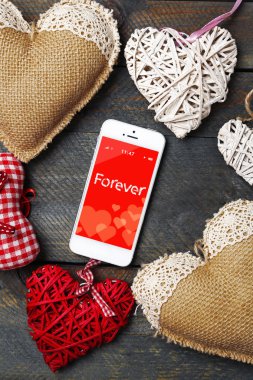 ahşap masa üzerinde yürekleri beyaz akıllı telefon.