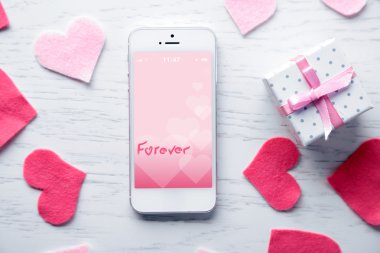 ahşap masa üzerinde yürekleri beyaz akıllı telefon.