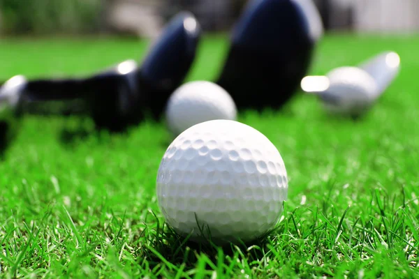 Different golf clubs in a row and balls on a green grass, close up — Stock Photo, Image