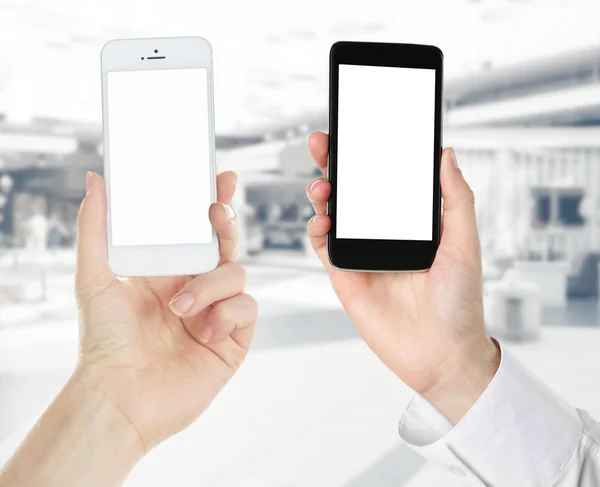 Manos sosteniendo teléfonos inteligentes en blanco y negro sobre fondo claro — Foto de Stock