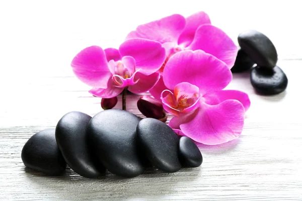 Beautiful composition of orchid and pebbles on white wooden background, close up — Stock Photo, Image