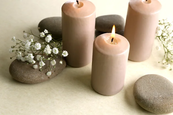 Mooie compositie van brandende kaarsen met keien en bloemen op witte achtergrond, close-up — Stockfoto