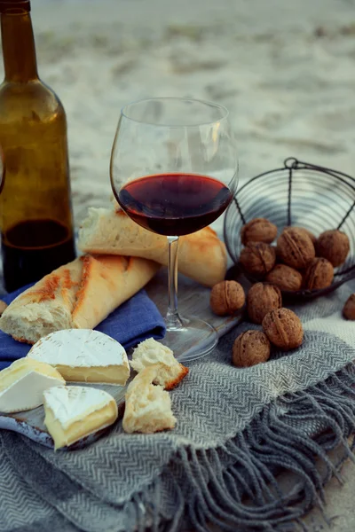 Nádherná romantická skladba červené víno, chléb a ořechy na písečné pláži — Stock fotografie