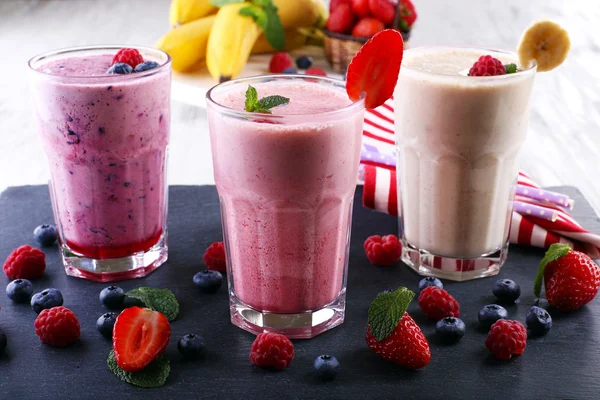 Milkshakes op snijplank met bessen op lichte achtergrond — Stockfoto