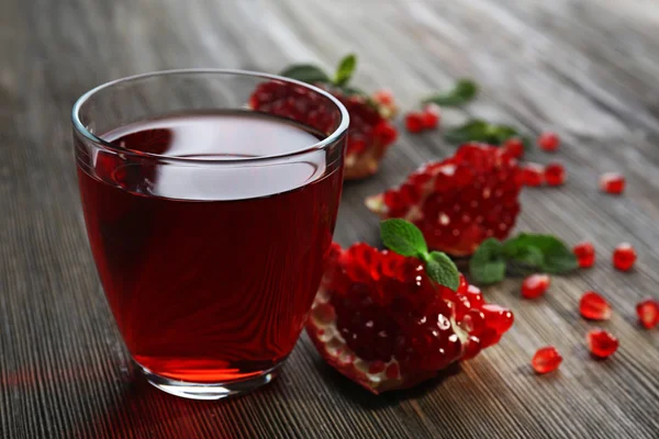 Un bicchiere di succhi saporiti e frutta granata, su fondo di legno — Foto Stock