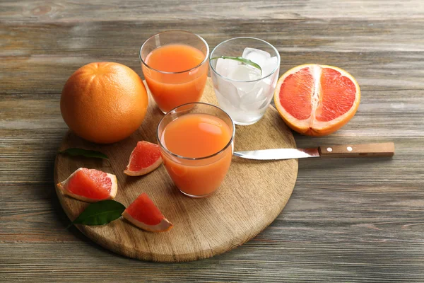 Succo di agrumi con ghiaccio e frutta fresca sul tagliere — Foto Stock