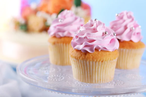 Cupcakes saborosos no carrinho e bolo, na mesa, no fundo de cor — Fotografia de Stock