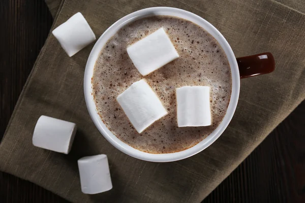 Cup of hot cacao with marshmallow on cotton serviette, close up