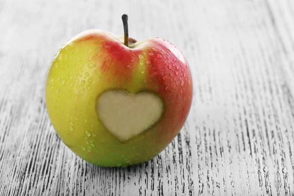 Äpple med hjärta på träbord — Stockfoto